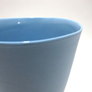 Viewed from slight angle above, a close-up of a very fine , tall turquoise porcelain tumbler, glazed on the inside with outside unglazed, available in Woburn Mosaic, contemporary art gallery